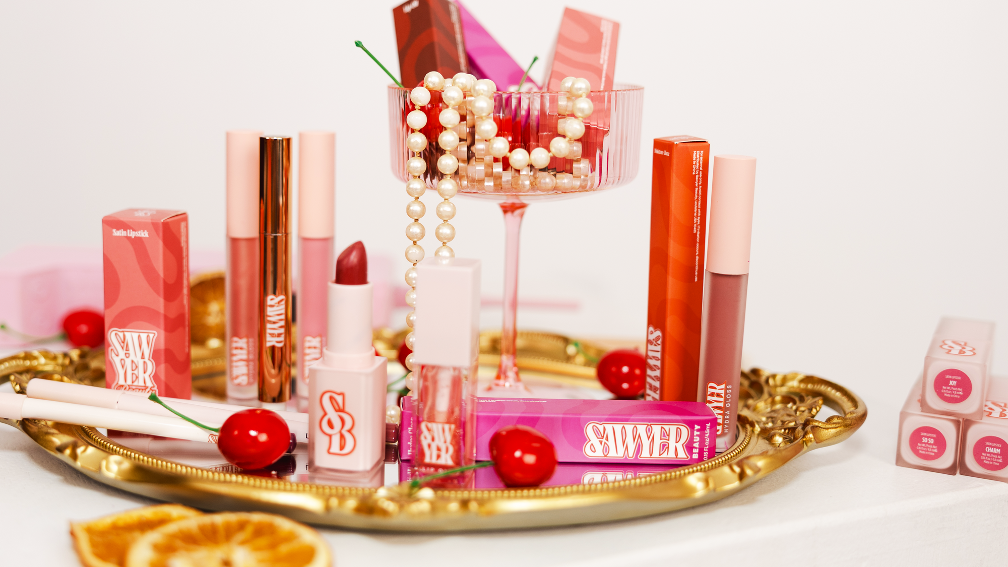 Collection of lip products on a gold tray with a white background